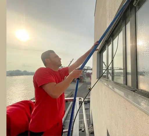 WSR-Mitarbeiter reinigt ein Fenster in großer Höhe mit einem Stangensystem